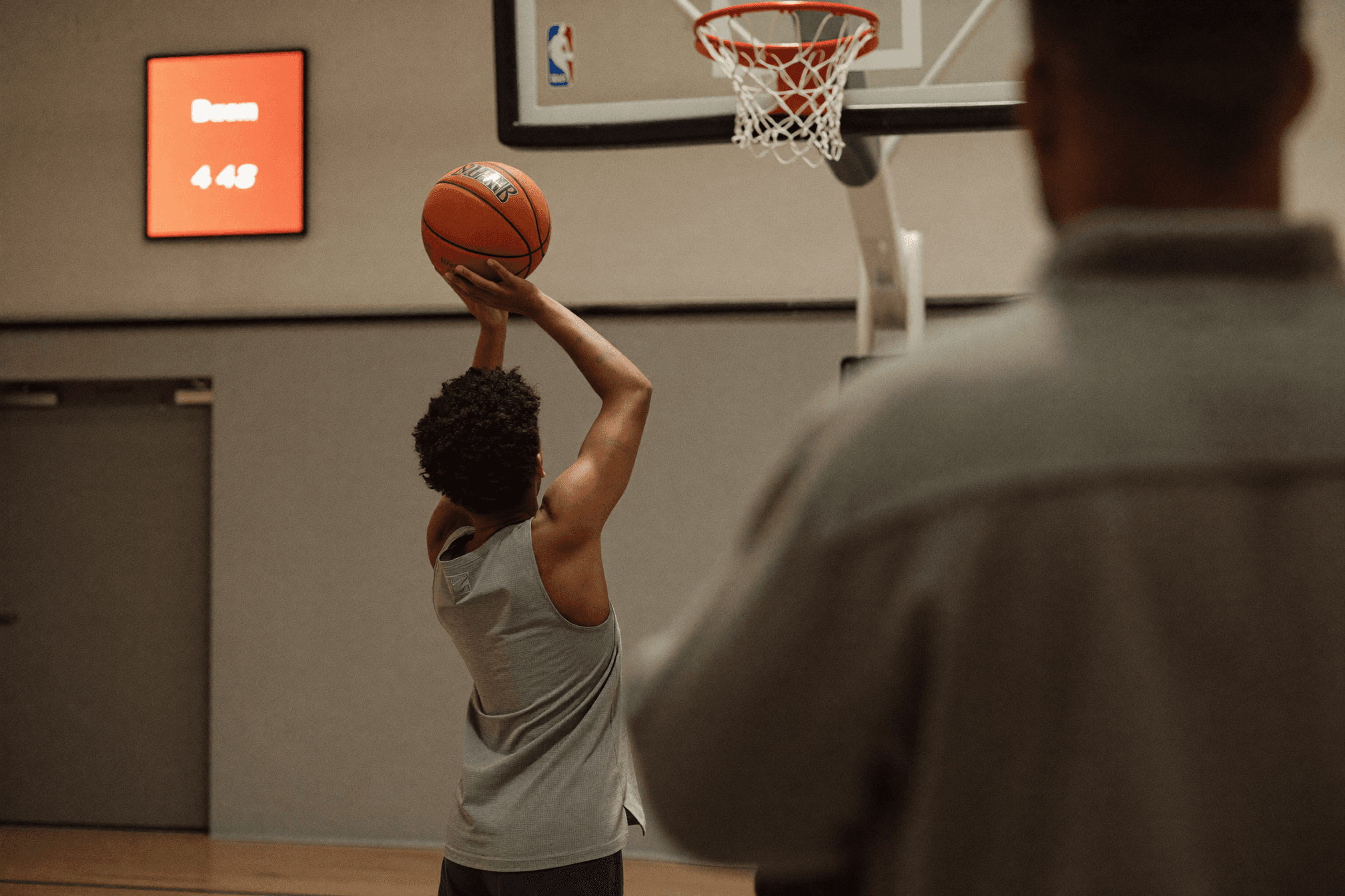 A coach guiding a player's shooting form during a one-on-one session